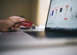 Person holding a credit card while shopping online on a laptop, indicating ecommerce transactions.